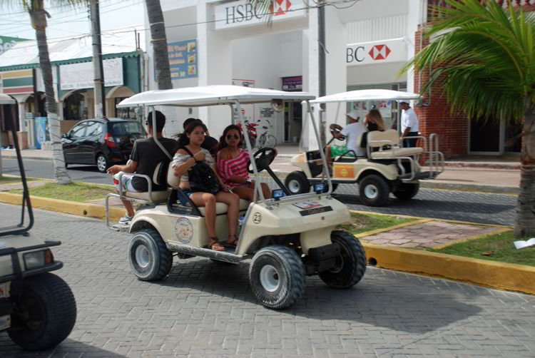 An image of people riding in a golf cart on Isla Mujeres. 