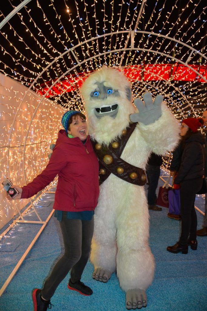 An image of a woman standing beside Yeti at the Aurora Winter Festival in Vancouver, BC, Canada.