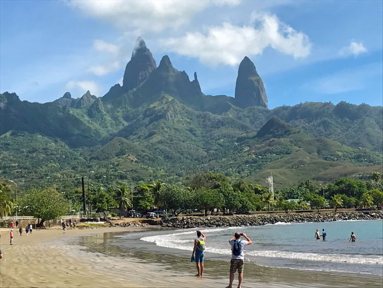 An image two people walking on a beach on Ua Pou Island, the third largest of the Marquesas Islands of French Polynesia. 