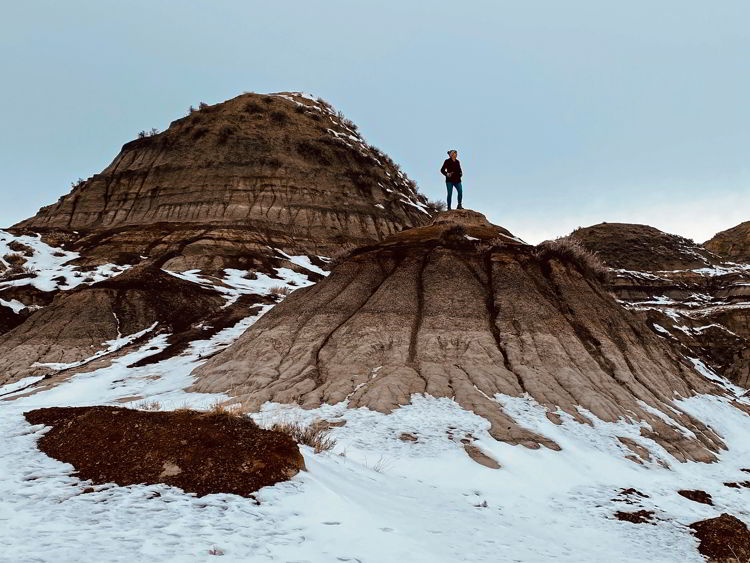 An image of a woman hiking in the badlands near Drumheller in the winter - things to do in Drumheller. 
