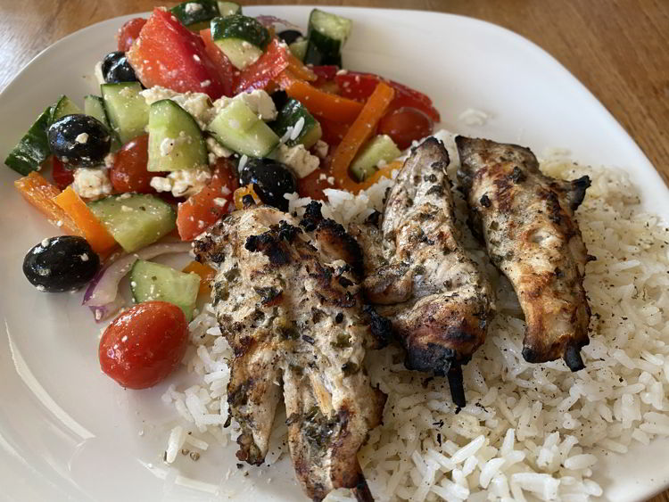 an image of Chicken souvlaki served with rice and Greek salad. 
