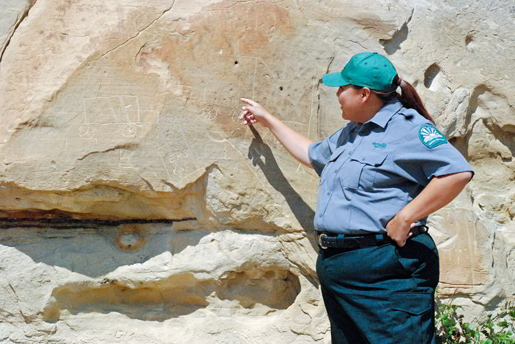 An image of an indigenous interpretor pointing at a petroglyph in Writing-on-Stone Provincial Park in Alberta, Canada. 