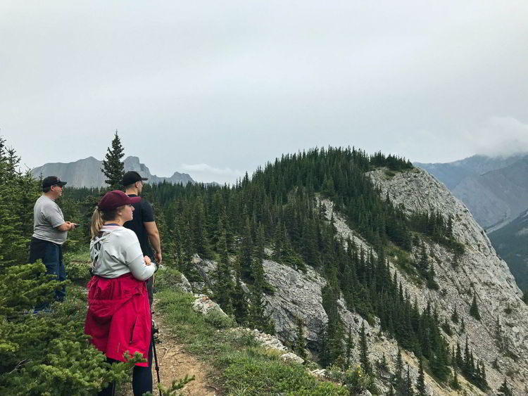 An image of three people taking in the view along the first section of the Heart Mountain Horseshoe trail near Canmore, Alberta. 