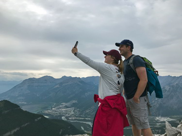 An image of a couple taking a selfie on the third summit of the Heart Mountain Horseshoe hike near Canmore, Alberta. 