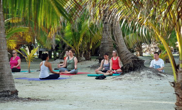 An image of a group of people doing a meditation exercise on a beach. - yoga retreat costa rica