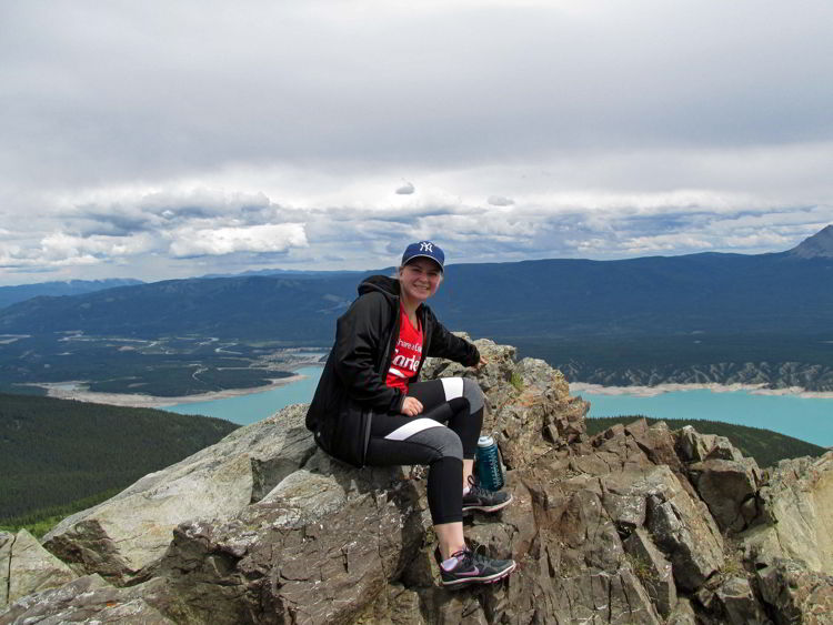 An image of a person sitting on a rocky viewpoint above Abraham Lake in Alberta, Canada. 