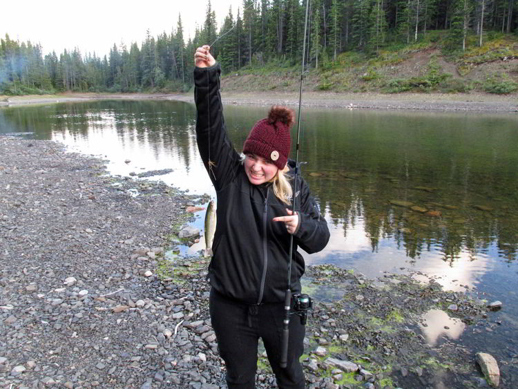 An image of a woman holding a brown trout at Allstones Lake in Alberta, Canada. 