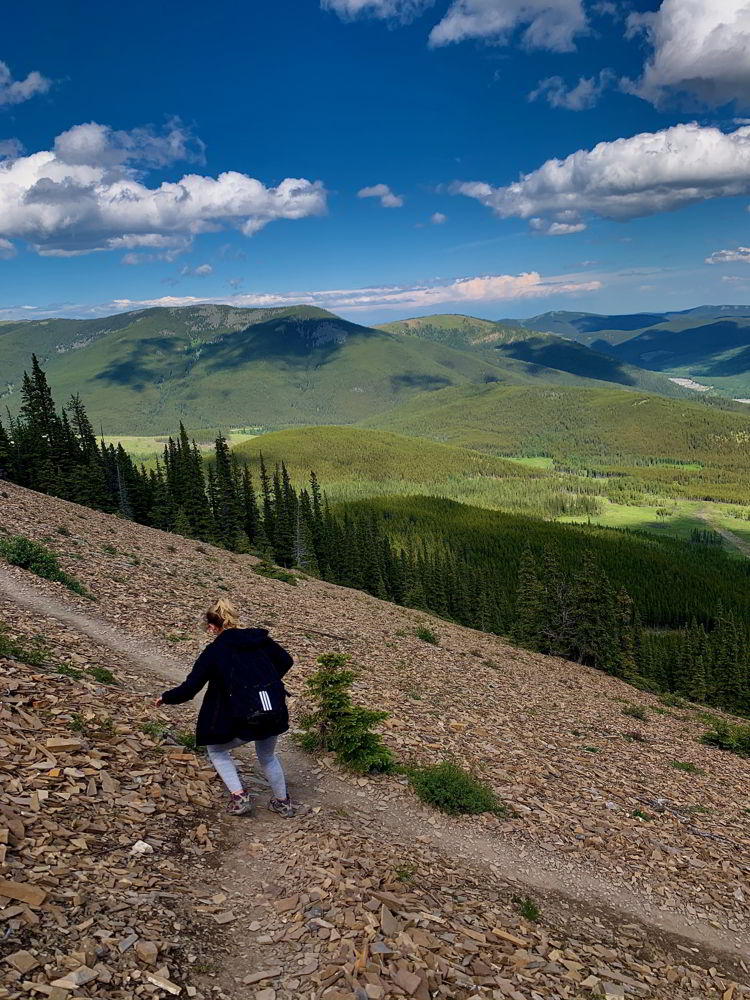 An image of a woman scrambling down the Nihahi Ridge trail in Kananaskis, Alberta, Canada. 
