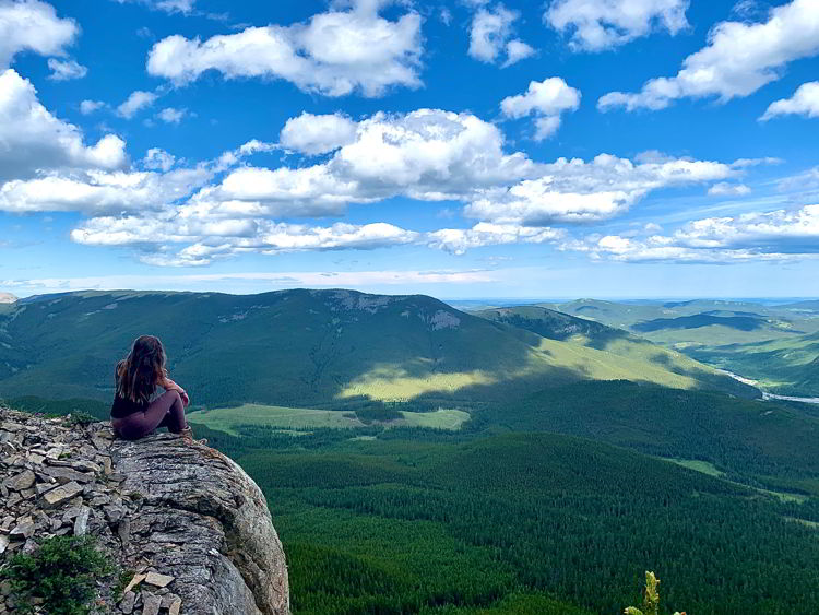 An image of a woman taking in the view at the top of Nihahi Ridge in Kananaskis, Alberta, Canada.