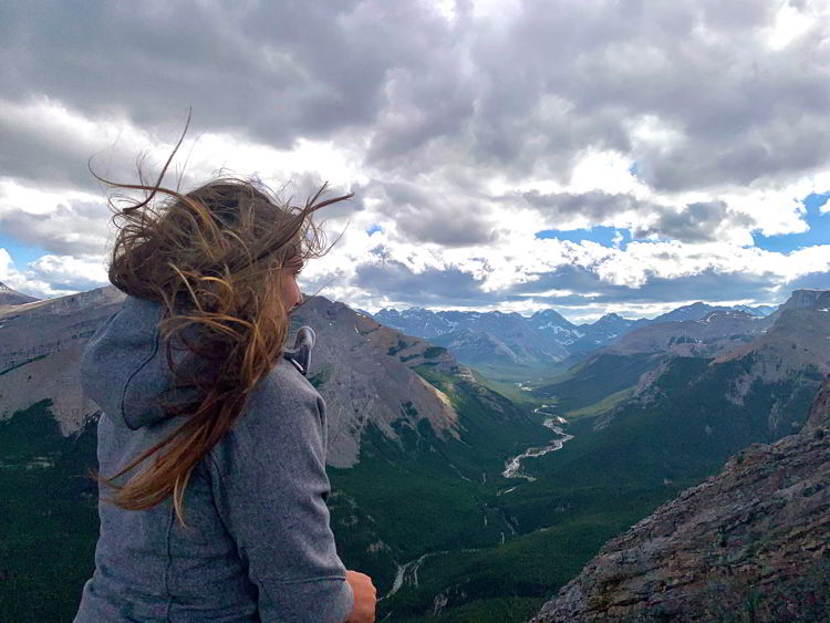 An image of a woman with her long hair blowing in the wind on Nahini Ridge in Kananaskis Country in Alberta, Canada. 