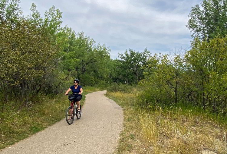 An image of a woman cycling through Police Point Park in Medicine Hat, Alberta, Canada. 