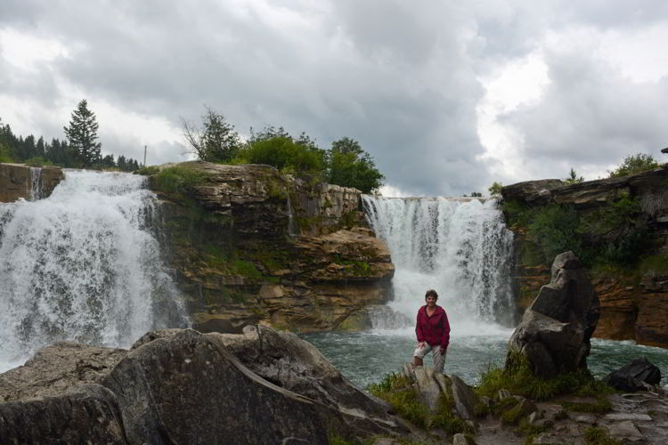 An image of a woman standing in front of Lundbreck Falls in Alberta, Canada. Crowsnest Pass road trip. 