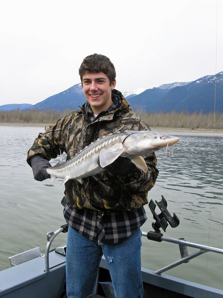 An image of a young man holding a white sturgeon. 