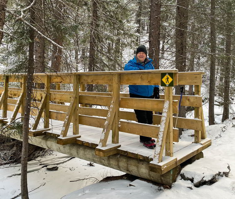 An image of a man standing on the wooden bridge on the Star Creek Falls hike in Crowsnest Pass, Alberta, Canada. 