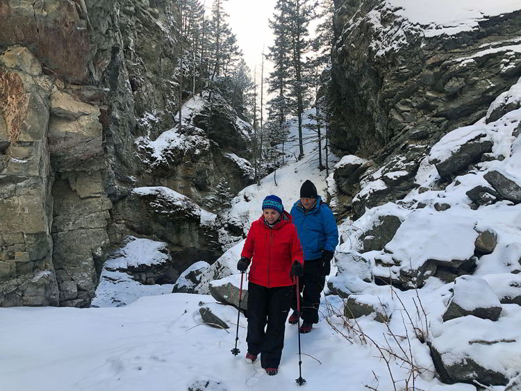 An image of a couple hiking in the canyon on the Star Creek Falls ice walk hike in Crowsnest Pass, Alberta, Canada.