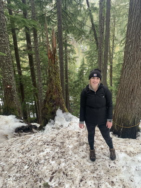 An image of a woman standing near the trailhead for Halfway Hot Springs in winter. 