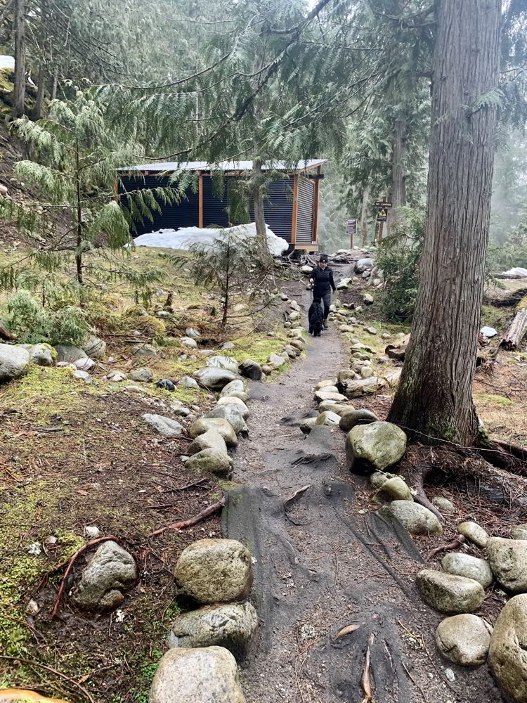 An image of a woman and a dog near the changerooms at Halfway Hot Springs in B.C., Canada.