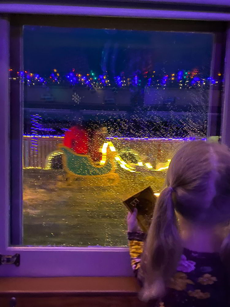 An image of young girl watching Santa in his sleigh and holding a golden ticket aboard the Polar Express Stettler train in Stettler, Alberta, Canada.
