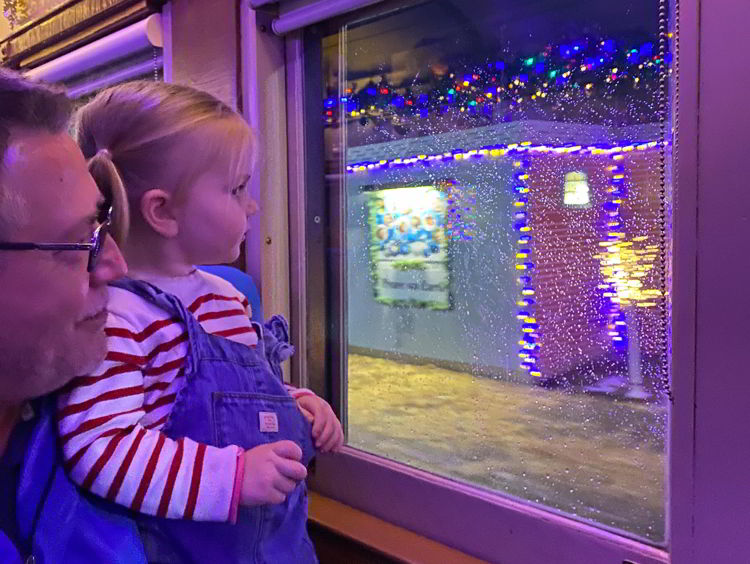 An image of a girl looking out the train window to see Christmas Town on the Polar Express in Stettler, Alberta, Canada. 