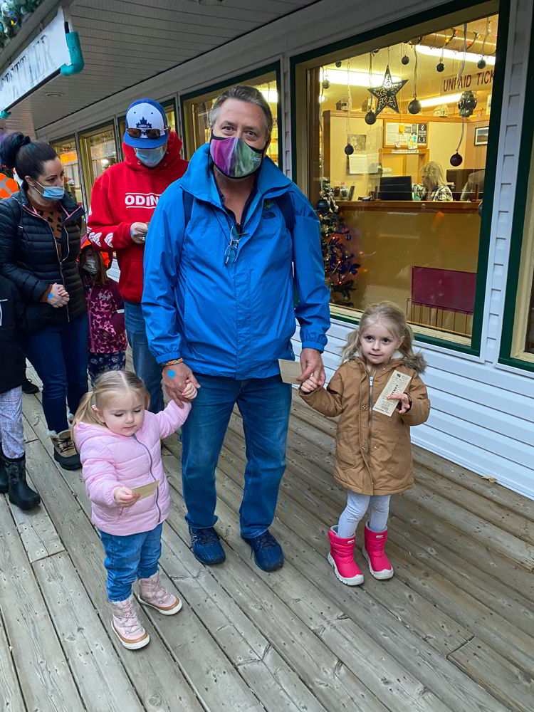 An image of two girls and a grandfather at the Polar Express Stettler train platform in Stettler, Alberta, Canada.