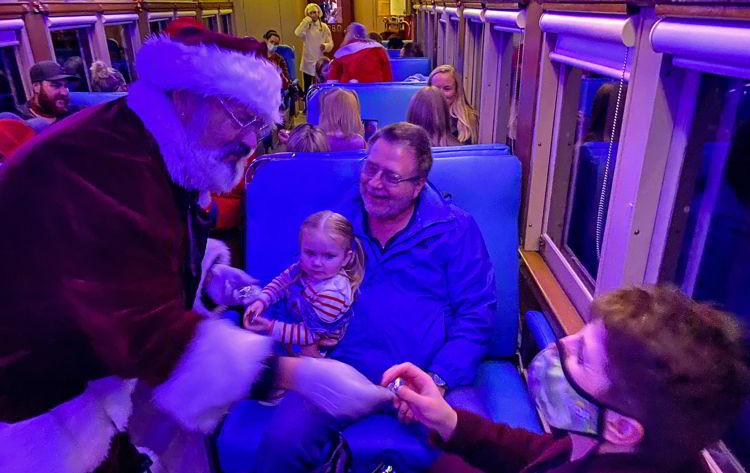 An image of a grandma receiving the first gift of Christmas on the Polar Express Stettler train in Stettler, Alberta, Canada. 