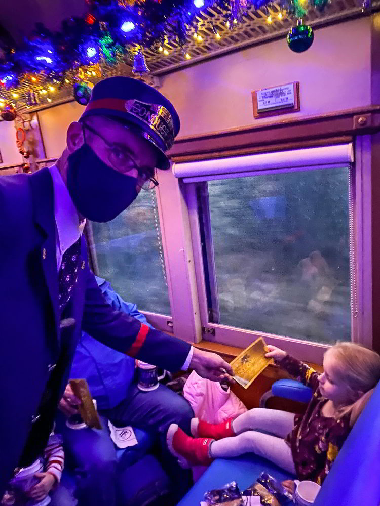An image of the conductor passing a young girl a golden ticket on the Polar Express Stettler train in Stettler, Alberta, Canada. 