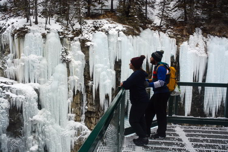 An image of a couple on the overlook at the Johnston Canyon hike in winter in Banff National Park in Alberta, Canada. 