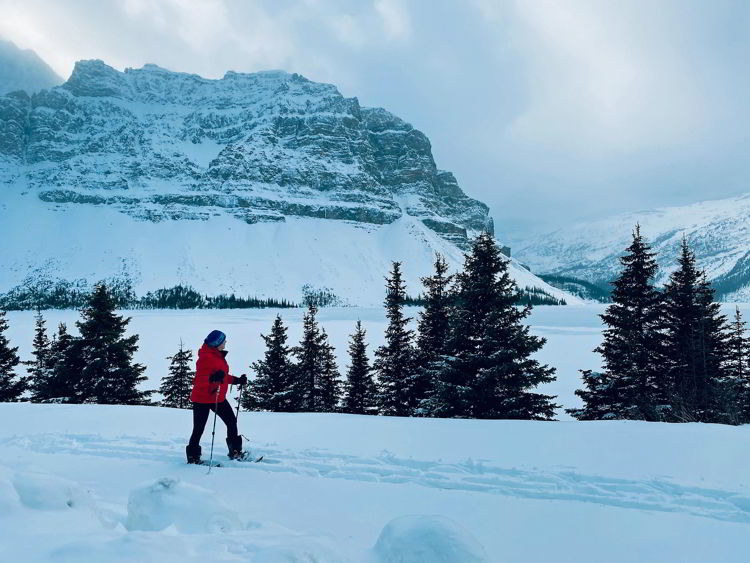 An image of a woman snowshoeing near Bow Lake in Banff National Park in Alberta, Canada. 