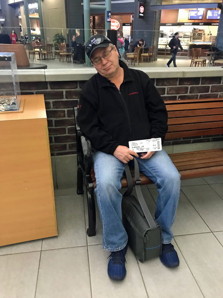 An image of a man sleeping at the airport - Swoop Airlines review