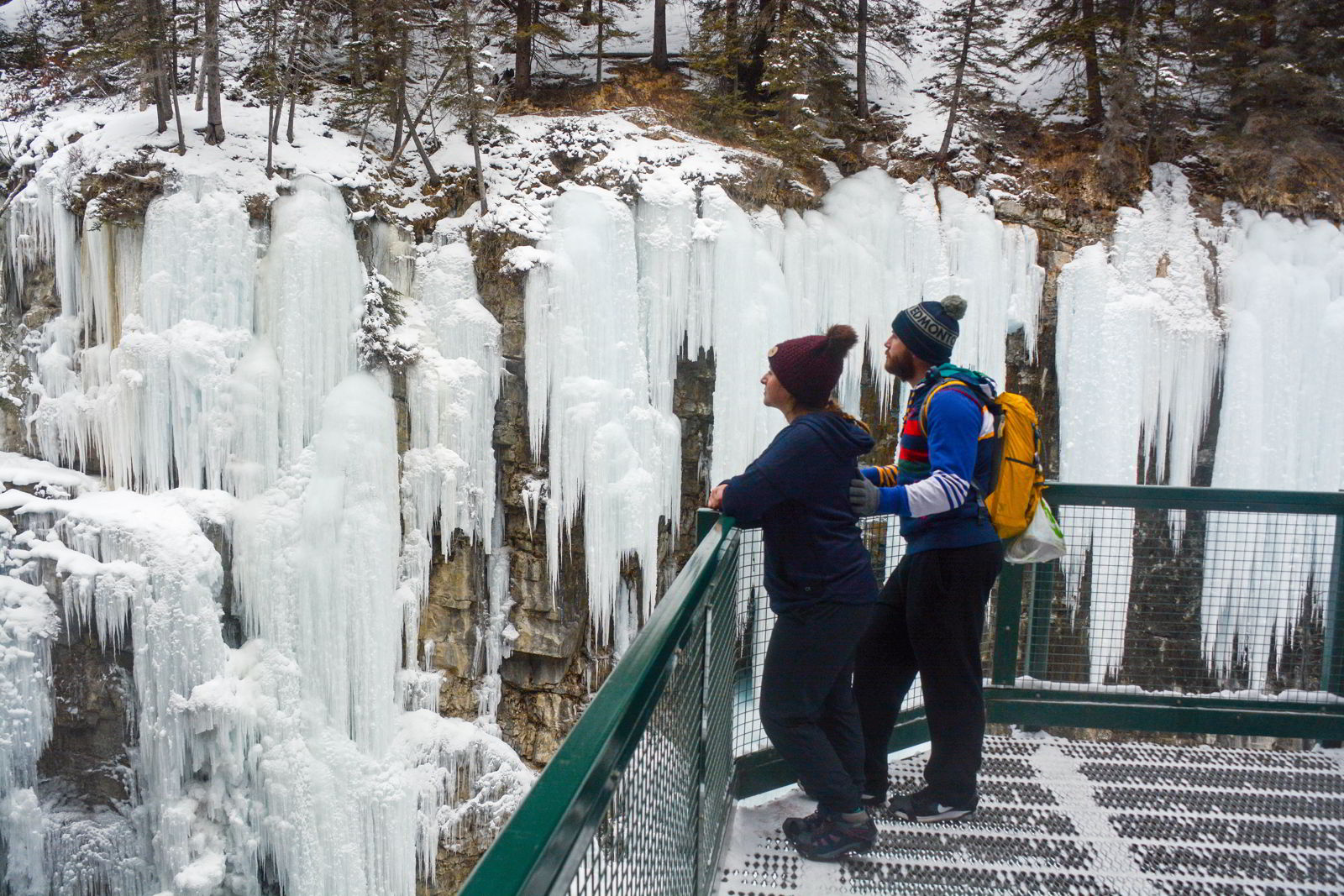 An image of two people looking at the ice formations in Johnston Canyon in Banff National Park - Johnston Canyon Winter Hike