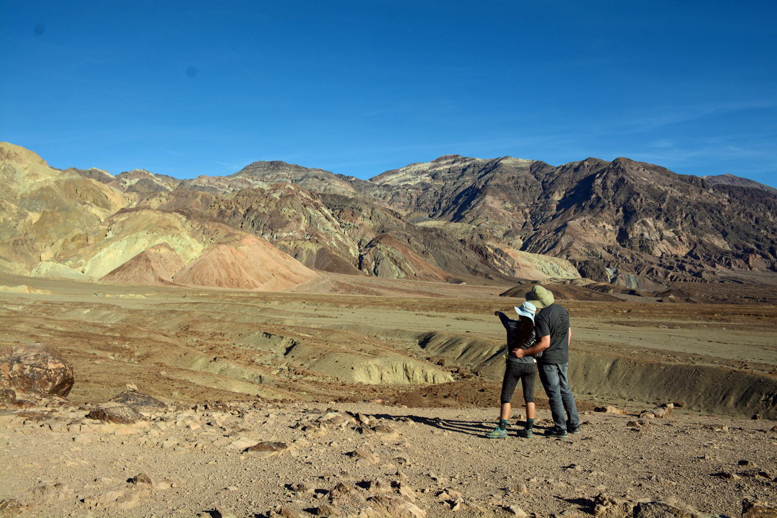 An image of a couple looking at the colors of the rock features at a point along the Artist's Drive in Death Valley National Park in California - Visiting Death Valley