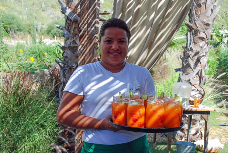 An image of a server at Flora Farms with a tray full of carrot margaritas.