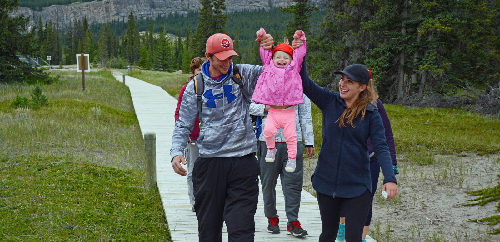 An image of a little girl being lifted into the air on a family hike near Siffleur Falls, Alberta - Glamping in Alberta.