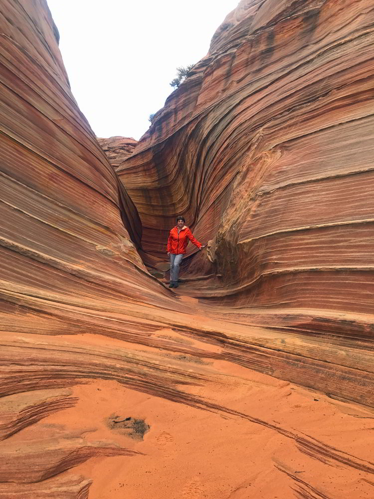 An image of a woman hiking near the wave in Coyote Buttes North Wilderness area in Arizona, USA. 