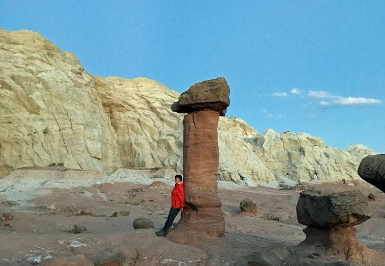 A photo of a woman standing next to one of the Toadstools in Grand Staircase-Escalante National Monument, Utah, USA