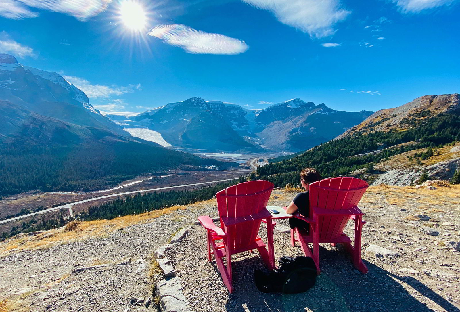 An image of someone sitting in a red chair and taking in the view of the Athabasca Glacier on the Wilcox Pass lookout hike in Jasper National Park, Alberta, Canada.