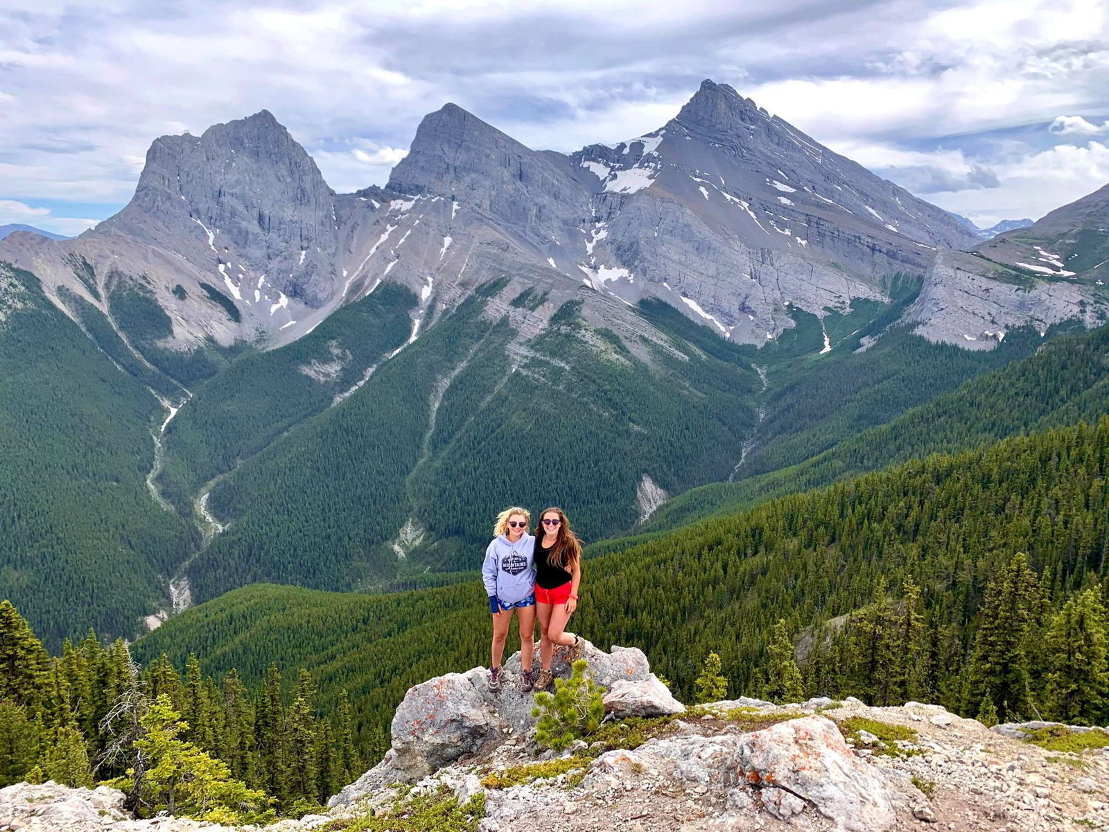 An image of two women standing on the top of the Grassi Knob Trail hike in Kananaskis, Alberta, Canada.