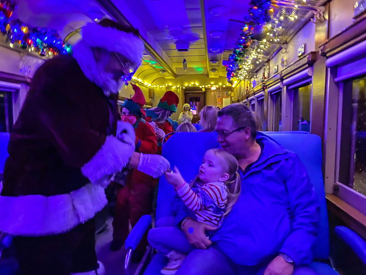 An image of a child receiving the first gift of Christmas on the Polar Express Stettler train.