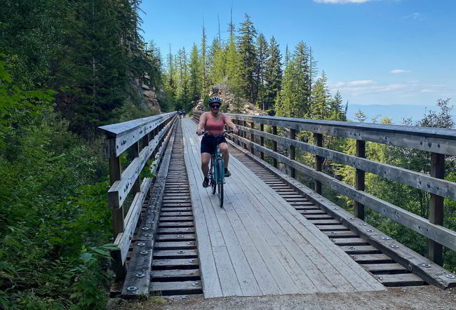 An image of a person cycling across a wooden trestle bridge in Myra Canyon near Kelowna, BC. 