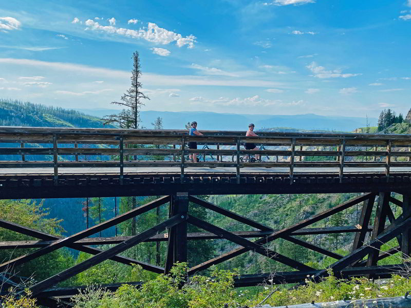 An image of two female cyclists on a trestle bridge in Myra Canyon near Kelowna, BC.