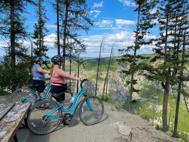 An image of two cyclists taking in the view on the Myra Canyon Trail near Kelowna, BC. 