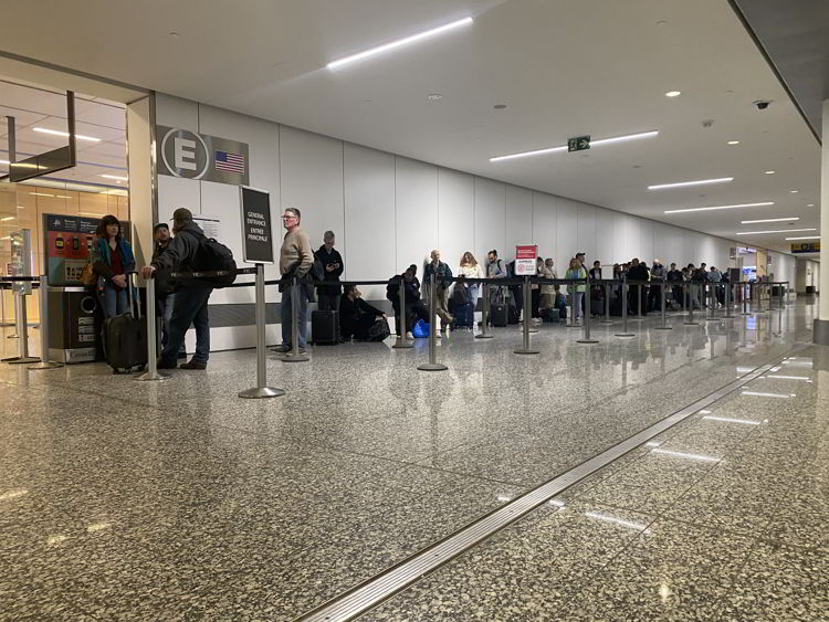 An image of people who did not make a reservation using YYC Express standing in a line at Calgary airport. 