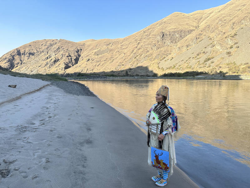 An Indigenous woman poses on the shore of the Snake River on hells Canyon jet boat tours.