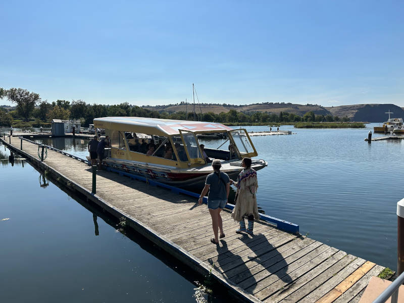 A woman and an Indigenous guide boarding a jet boat.